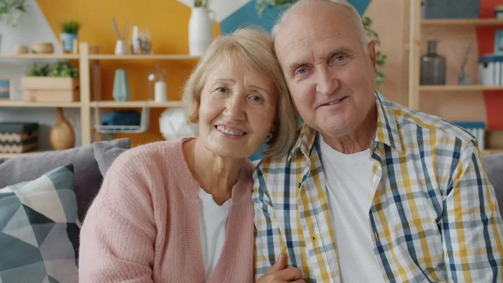An elderly couple smiling warmly together at home