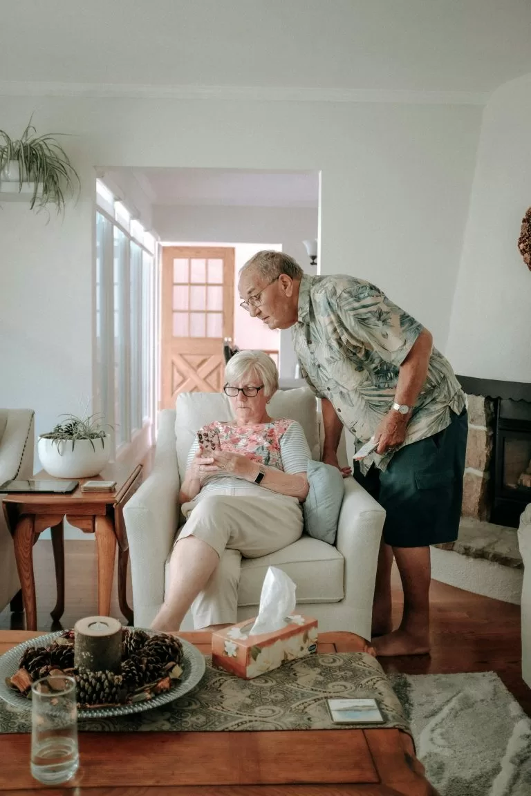 An elderly couple at home together, looking through messages and paperwork