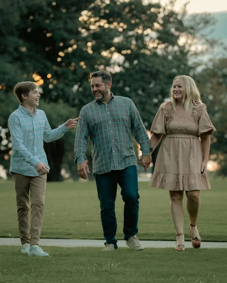 A family of three laughing together as they walk outdoors