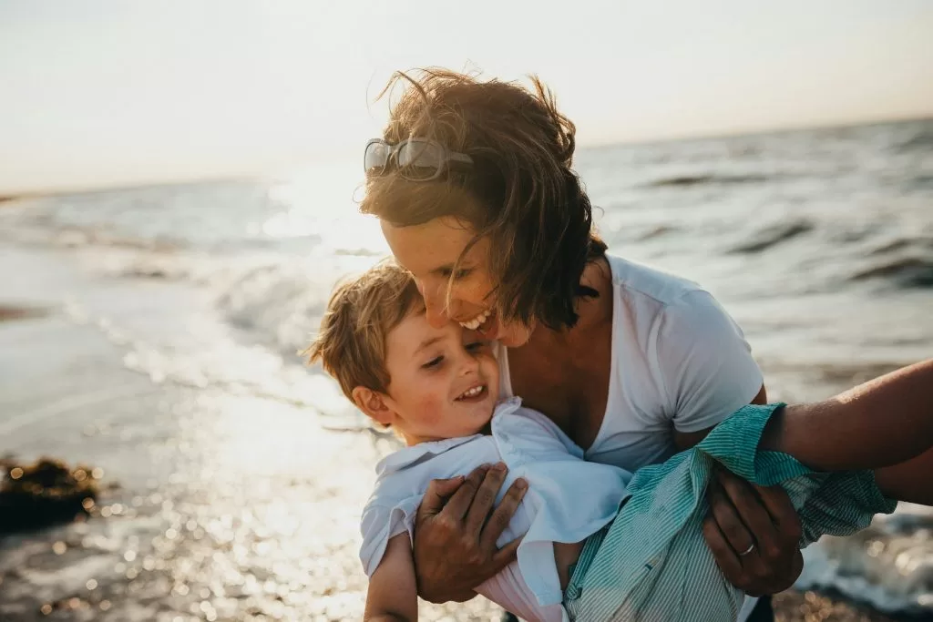 A mother embracing her young son at the beach at sunset